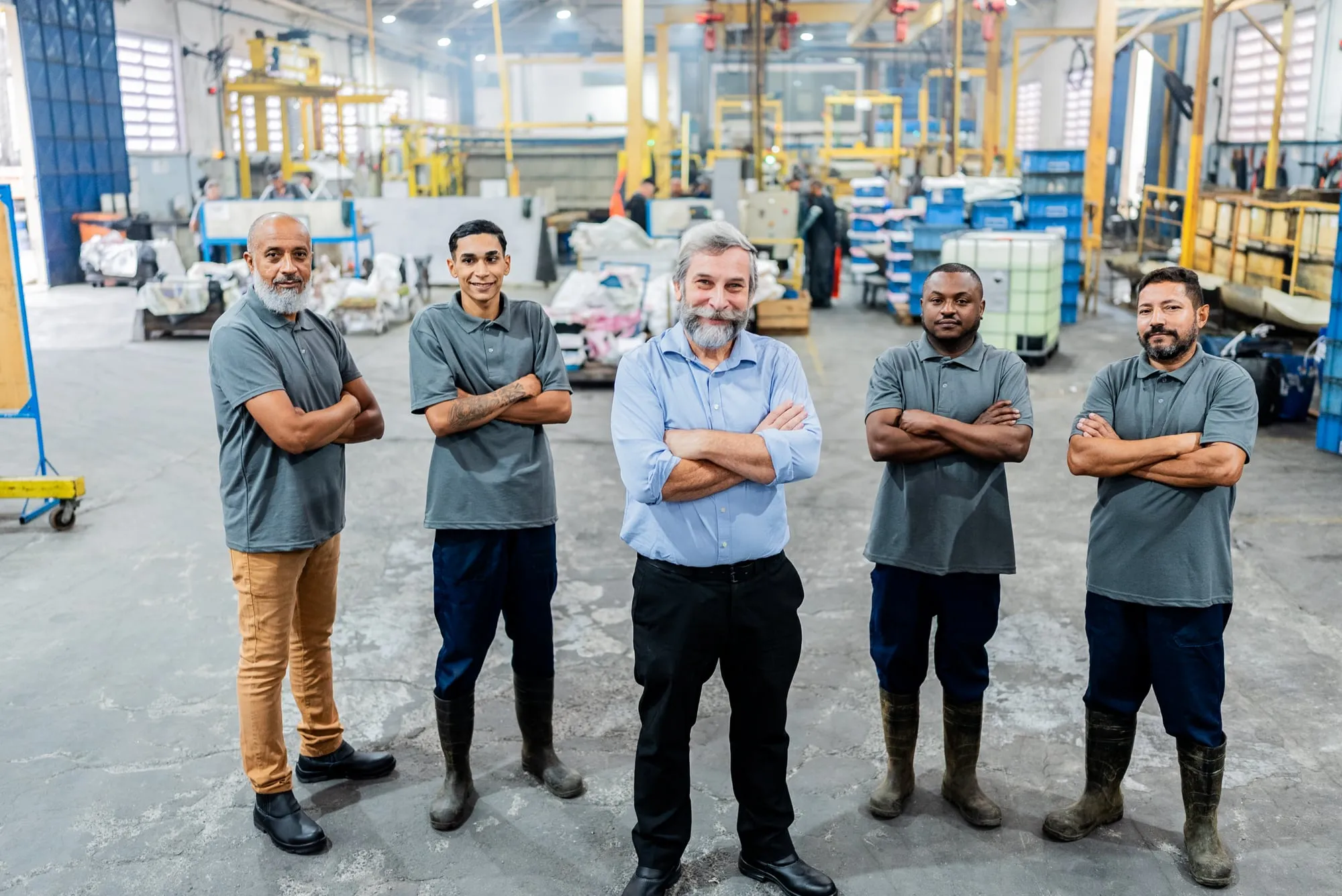 Equipe de operadores técnicos da Sapucaia posando no chão de fábrica, representando o conhecimento humano por trás do tratamento de superfícies de metais