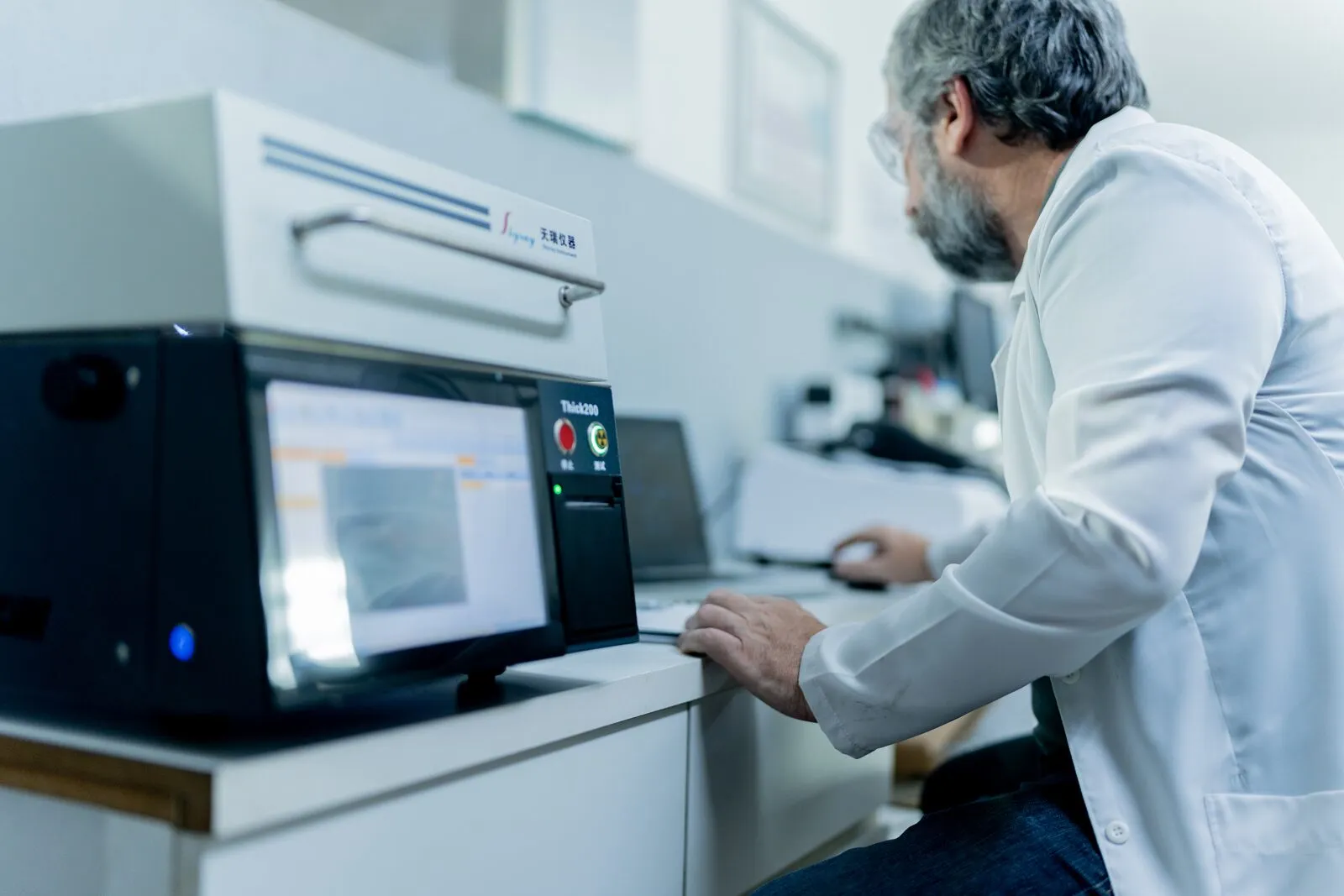Espectrômetro de fluorescência de raios X do laboratório, com o analista ao lado