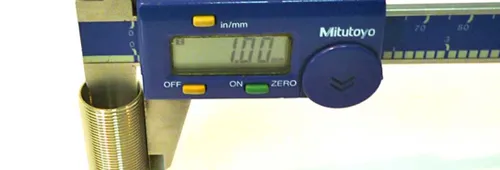 Paquímetro digital medindo o diâmetro externo de um tubo roscado, com a leitura no mostrador